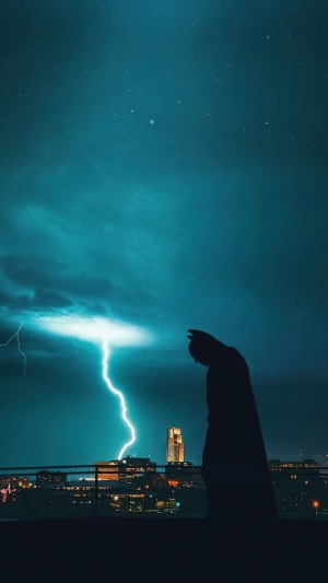 Batman silhouette against lightning and city skyline
