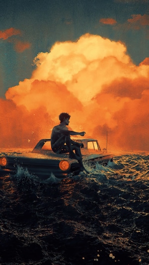 Man sitting on a car in the ocean with orange clouds
