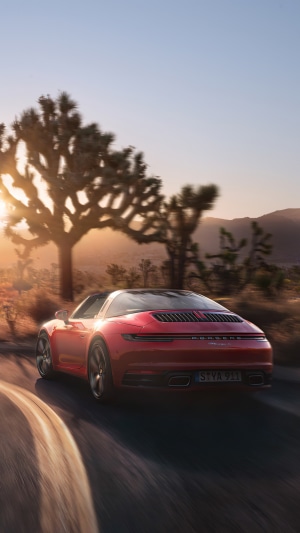 Red Porsche 911 Targa driving in desert at sunset