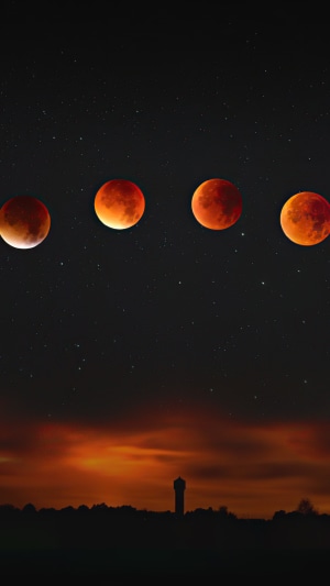 Time-lapse of a blood moon eclipse over a silhouetted landscape