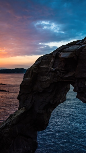 Rock arch over the ocean at sunset