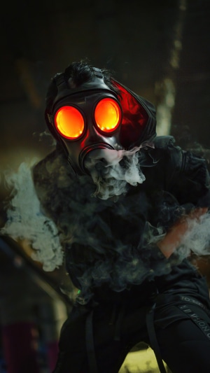 Person in gas mask with glowing eyes and smoke