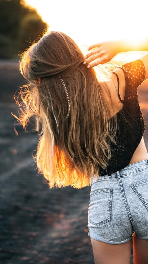 Woman with blonde hair in denim shorts at sunset