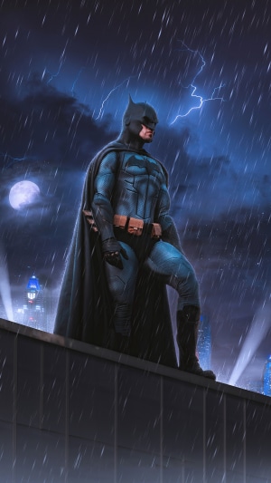 Batman standing on a rooftop in the rain