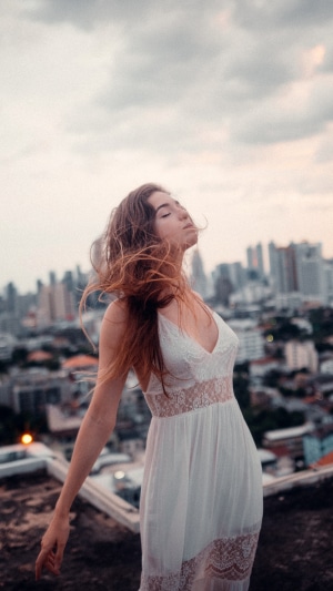 Woman in white dress on rooftop with city skyline