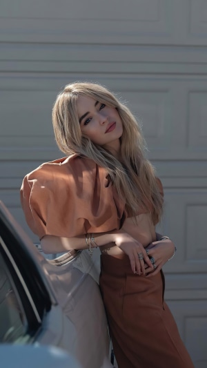 Sabrina Carpenter posing by a car