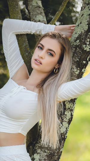 Model in white dress leaning on a tree