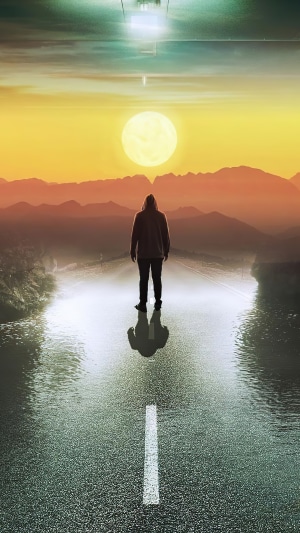 Person in hoodie on road at sunset