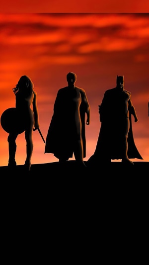 Wonder Woman, Superman, and Batman silhouetted against a sunset