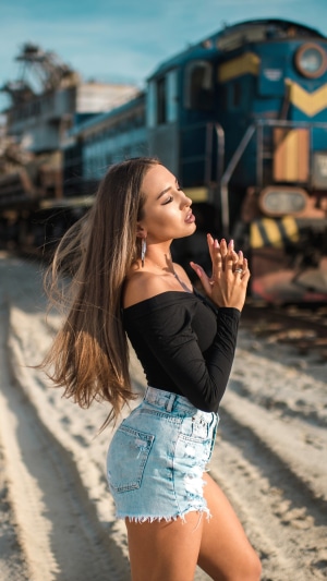 Model in denim shorts and black top near train