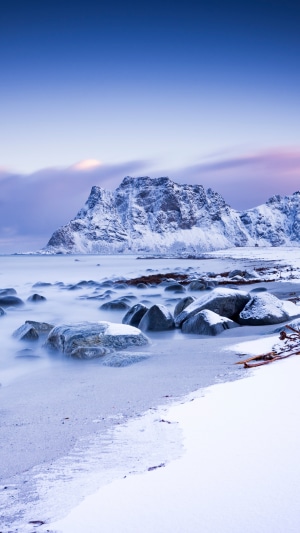 Snow-covered mountains and rocky beach in winter