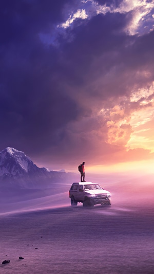 Person standing on a car in a desert landscape