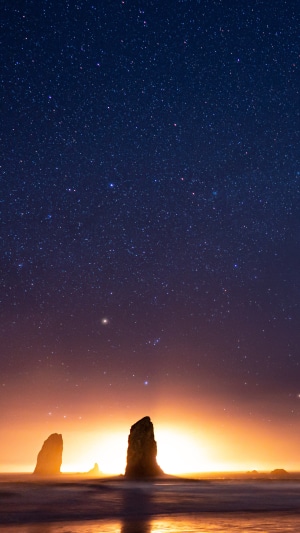 Ocean rocks under starry sky at sunset 4K