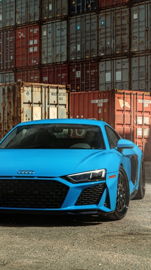 Blue Audi R8 parked in front of shipping containers