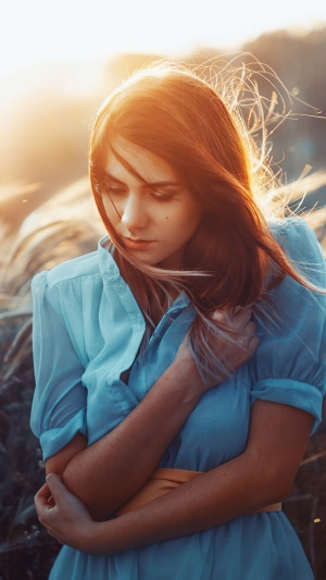 Redhead girl in blue dress in field at sunset 4K