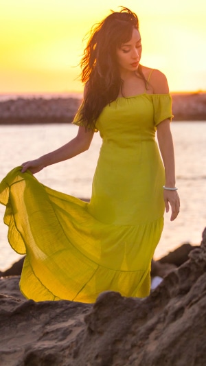 Woman in yellow dress by the sea at sunset