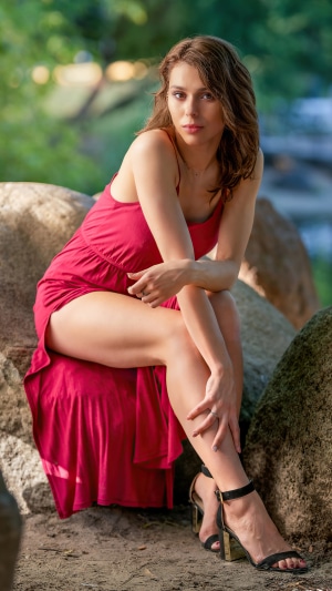 Woman in red dress sitting on rocks