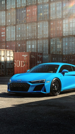 Blue Audi R8 parked in front of shipping containers