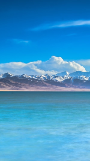 Turquoise lake and snow-capped mountains under blue sky