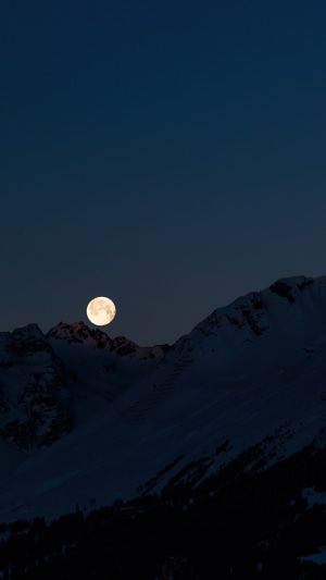 Full moon over snowy mountains