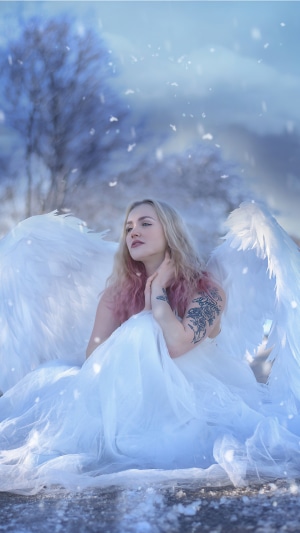 Angel with white wings in a snowy landscape