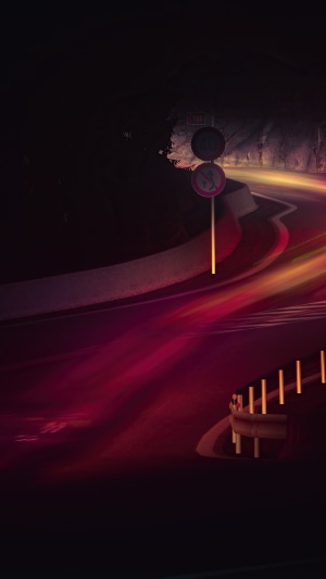 Long exposure photography of a winding road at night with light trails