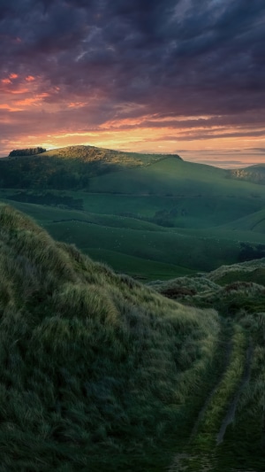 Rolling green hills and dramatic sunset sky