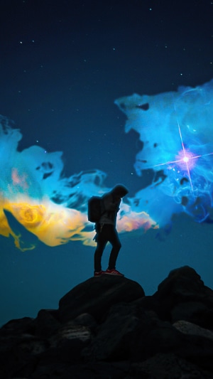 Silhouette of a person on rocks with nebula background
