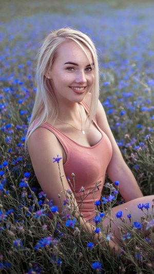 Blonde woman smiling in a field of blue flowers