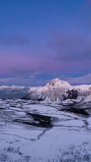 Snow-covered mountains and landscape under a purple sky