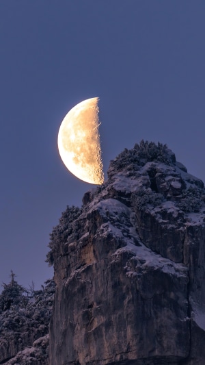 Half moon over snow-covered mountains