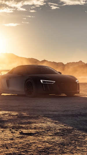 Black Audi R8 on a dusty road at sunset