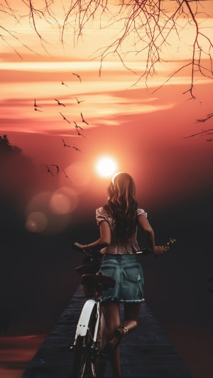 Girl with bicycle at sunset