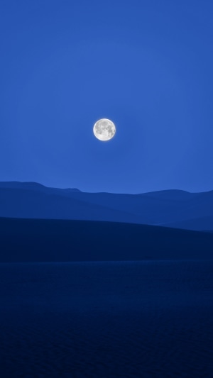 Full moon over desert dunes at night