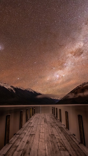 Wooden pier under the Milky Way and mountains