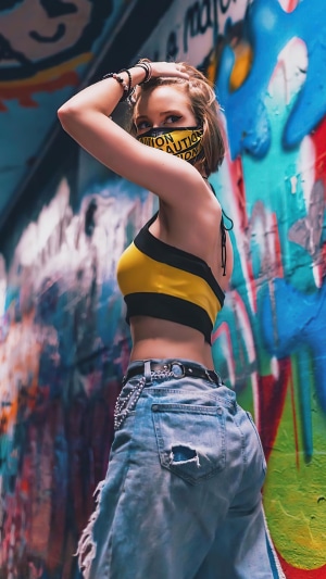 Model wearing a yellow and black top and ripped jeans