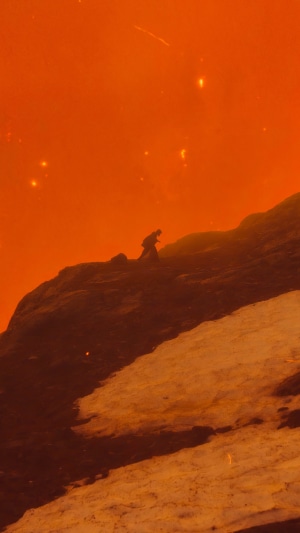 Person climbing a rocky, snowy mountain under an orange sky