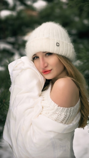 Girl in white hat and sweater in snow