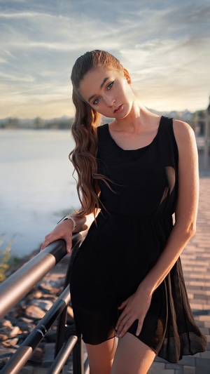 Girl in black dress by the water