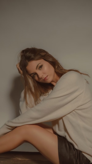 Victoria Justice sitting with hand on head