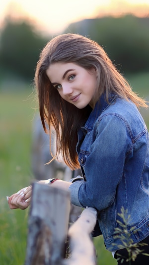 Girl in denim jacket leaning on fence