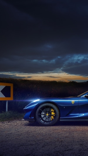 Blue Ferrari 812 parked on a dirt road at dusk