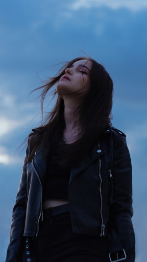 Girl in leather jacket against cloudy sky