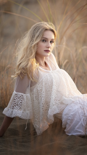 Blonde girl in white dress in tall grass
