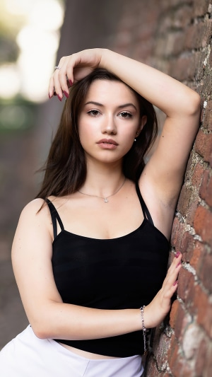 Young woman leaning against a brick wall