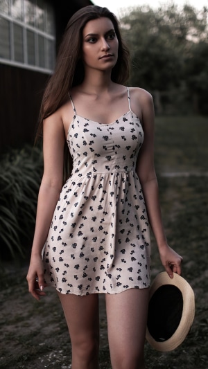 Woman in a floral dress holding a hat