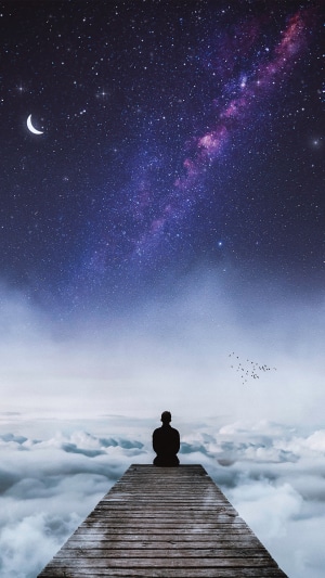 Man sitting on a pier under the Milky Way