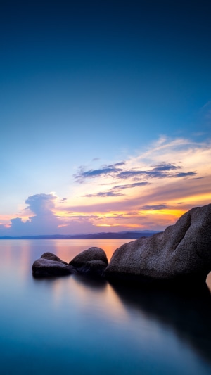 Rocks in calm lake at sunset