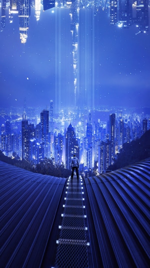 Man in hoodie on walkway overlooking city at night