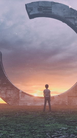 Boy standing before a large circular structure at sunset